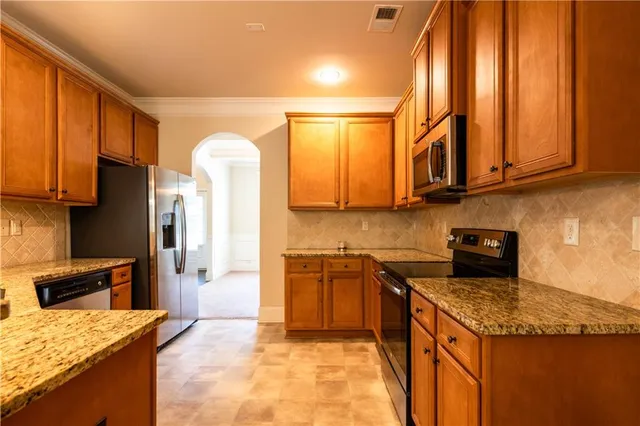 a kitchen with stainless steel appliances granite countertop a sink a stove and a refrigerator