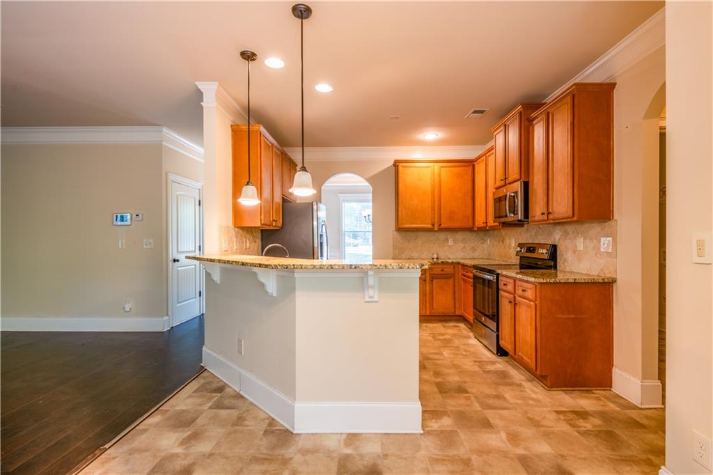 1412 Turnbridge Walk Hampton, GA 30228 - Photo 13 of 40 a kitchen with stainless steel appliances granite countertop a sink a stove and a wooden floors
