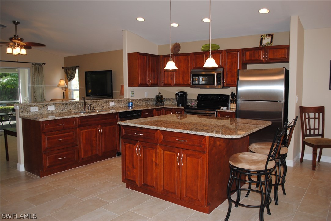 5891 Tarpon Road Bokeelia, FL 33922 - Photo 12 of 25 a kitchen with stainless steel appliances granite countertop a sink a stove a dining table and chairs
