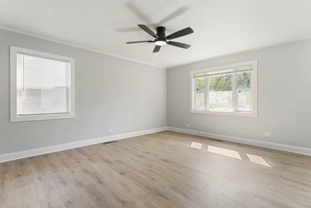 a view of empty room with wooden floor and fan