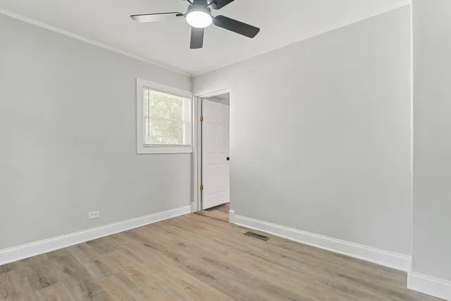 an empty room with wooden floor fan and windows