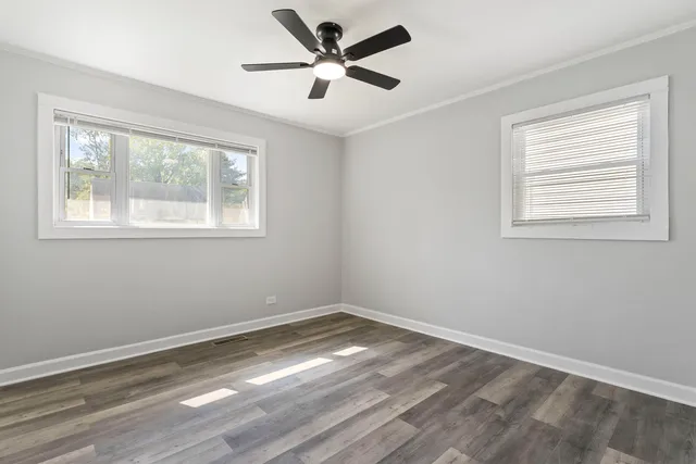 a view of empty room with wooden floor and fan