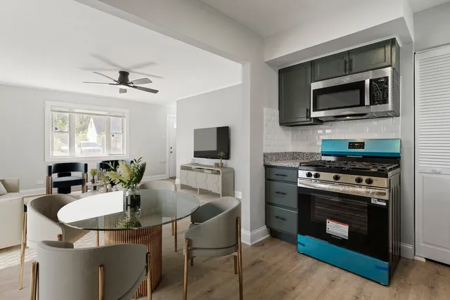 a kitchen with stainless steel appliances a stove a microwave sink a refrigerator dining table and chairs