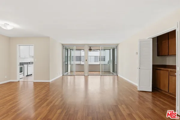 a view of an empty room with window and wooden floor