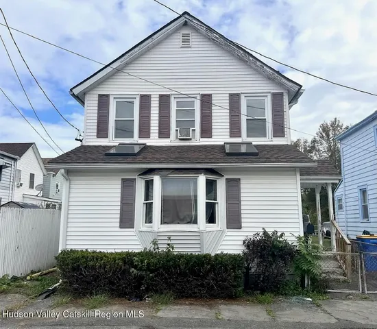 a view of a white house with large windows and potted plants