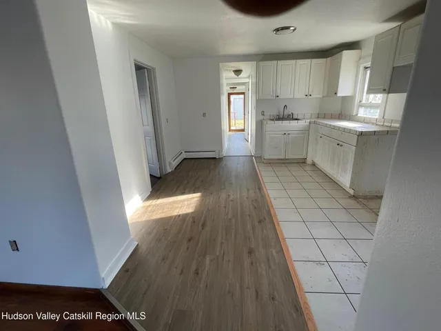 a view of a kitchen with white cabinets and wooden floor