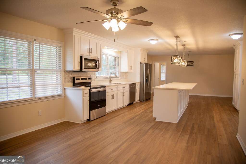 503 Satilla Church Road Baxley, GA 31513 - Photo 21 of 70 a kitchen with stainless steel appliances kitchen island wooden floors and white cabinets