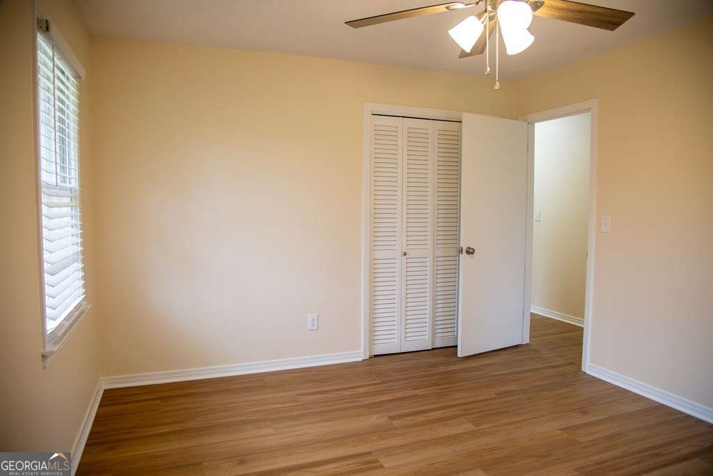 503 Satilla Church Road Baxley, GA 31513 - Photo 25 of 70 an empty room with wooden floor chandelier fan and windows