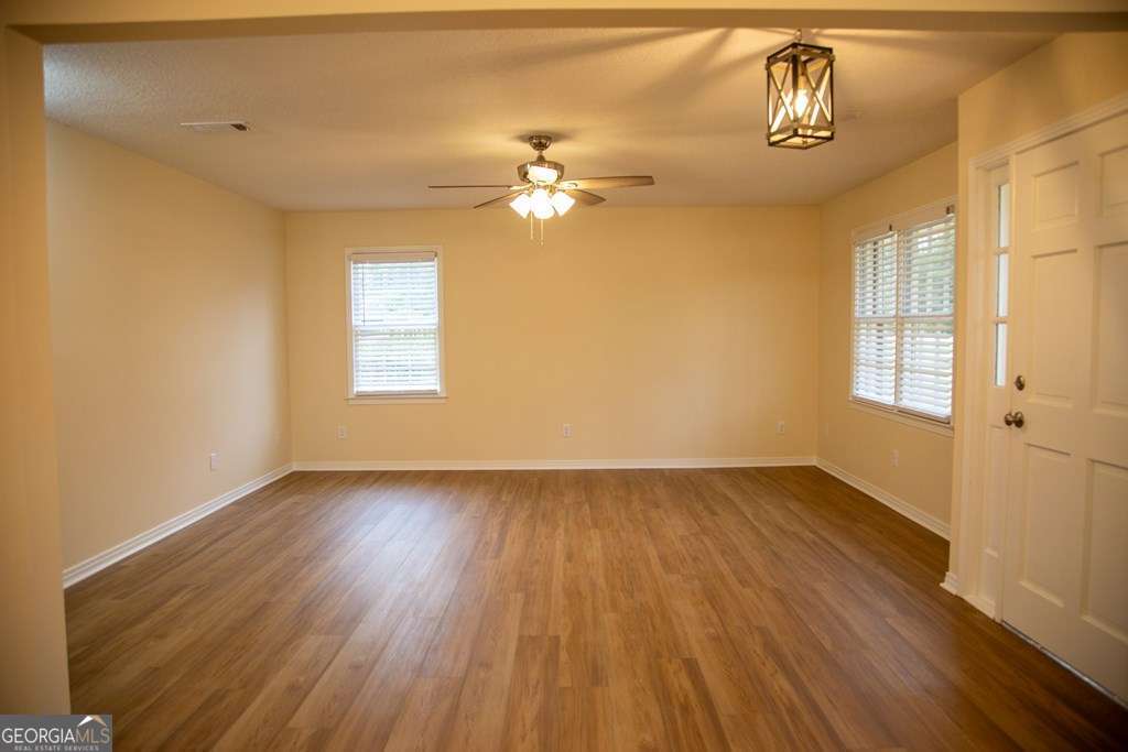 503 Satilla Church Road Baxley, GA 31513 - Photo 43 of 70 an empty room with wooden floor chandelier fan and windows