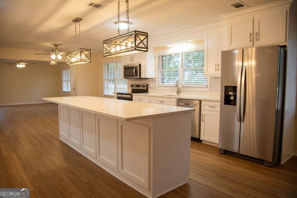 503 Satilla Church Road Baxley, GA 31513 - Photo 53 of 70 a kitchen with stainless steel appliances a refrigerator a sink dishwasher a stove and white cabinets with wooden floor