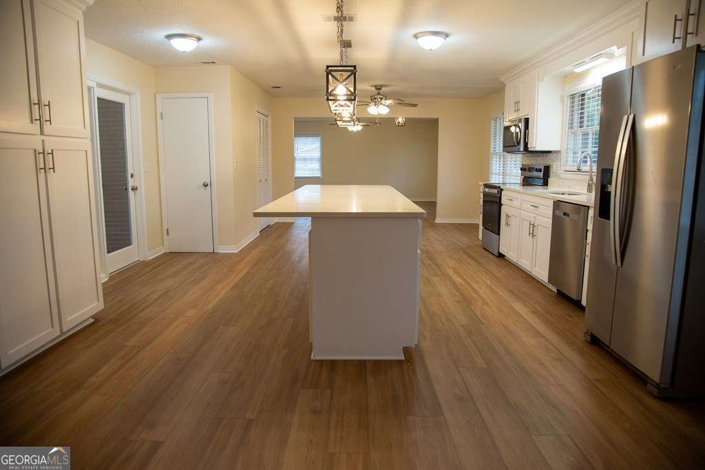 503 Satilla Church Road Baxley, GA 31513 - Photo 54 of 70 a open kitchen with a refrigerator a sink dishwasher a dining table and chairs with wooden floor