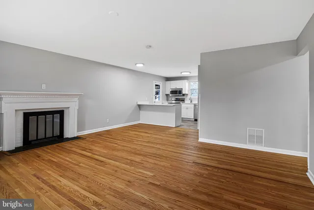 a view of empty room with wooden floor and fireplace