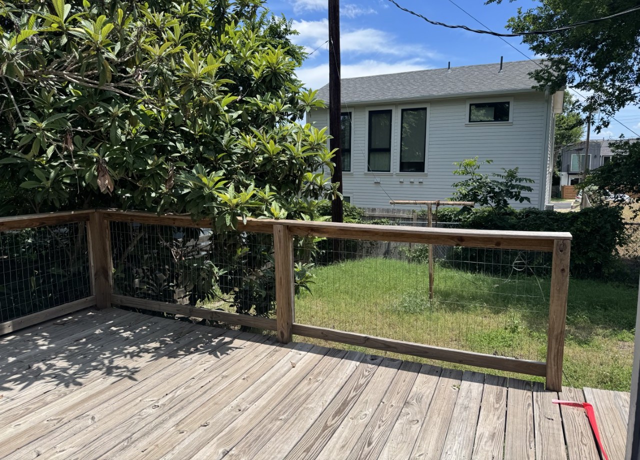 1813 Rhodes Road Austin, TX 78721 - Photo 12 of 14 A spacious wooden deck provides an elevated outdoor retreat with a verdant backdrop and ample natural light.