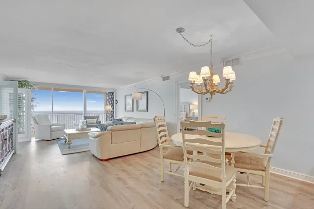 a dining room with wooden floor a chandelier a wooden table and chairs