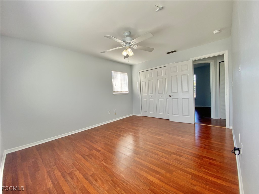 260 13th Street Southwest Naples, FL 34117 - Photo 20 of 29 an empty room with wooden floor ceiling fan and windows