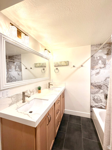 3626 Riverstone Road Mapleton, UT 84664 - Photo 44 of 58 Full bath featuring double vanity, a textured ceiling, a combined bath / shower with marble appearance, and dark tile patterned floors