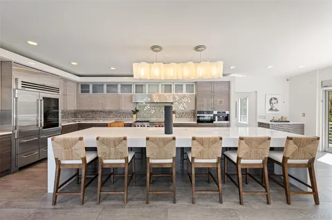 a large kitchen with stainless steel appliances a large counter top a stove a chimney a sink and a refrigerator