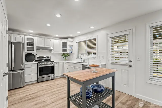 a kitchen with kitchen island a stove a sink a refrigerator wooden floor cabinets and dining table