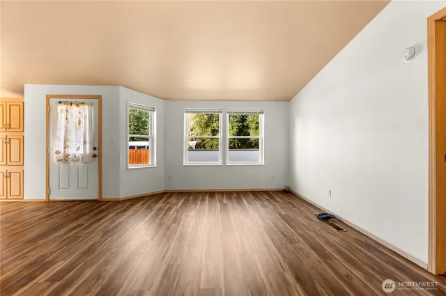 an empty room with wooden floor and windows