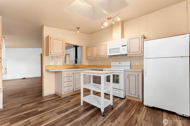 a kitchen with stainless steel appliances a stove a refrigerator and white cabinets with wooden floor