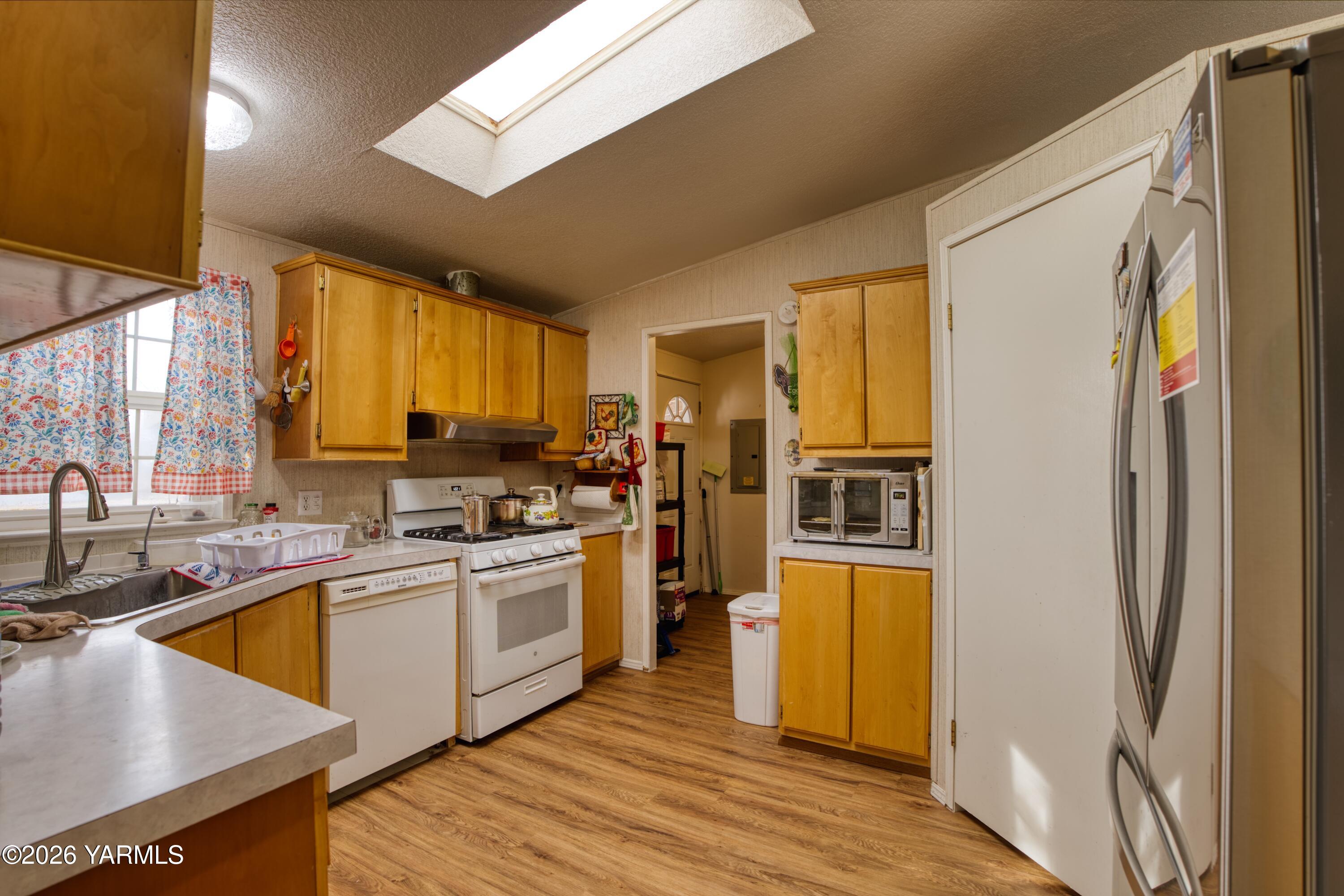1383 Puterbaugh Road Grandview, WA 98930 - Photo 5 of 19 a kitchen with stainless steel appliances granite countertop a refrigerator a sink dishwasher a stove and a dining table with wooden floor