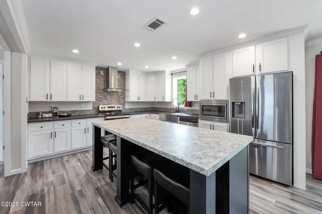 a kitchen with a center island appliances and cabinets