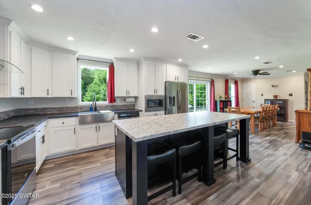 a kitchen with stainless steel appliances granite countertop a kitchen island a stove a table and chairs in it