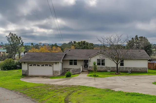 a view of a house with a big yard and large tree