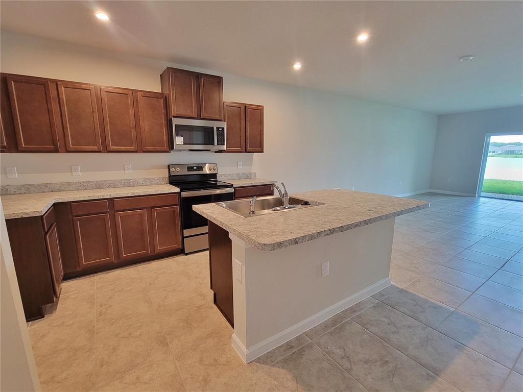 18008 Turning Leaf Circle Land O Lakes, FL 34638 - Photo 20 of 54 a kitchen with stainless steel appliances granite countertop a sink stove microwave and refrigerator