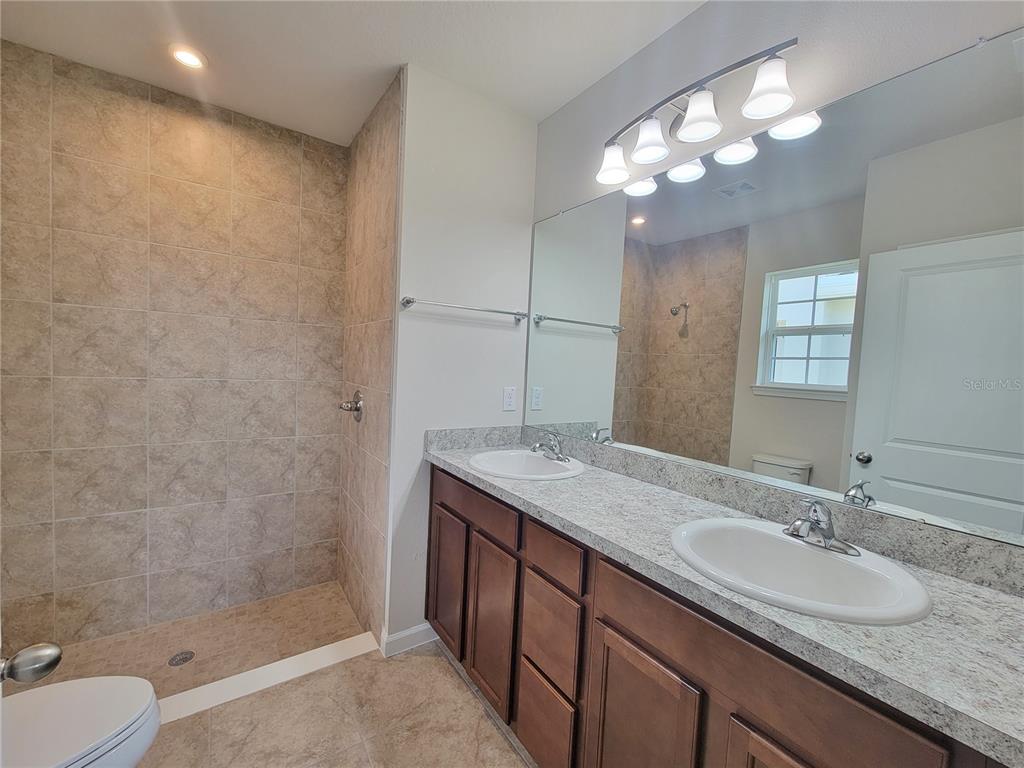 18008 Turning Leaf Circle Land O Lakes, FL 34638 - Photo 32 of 54 a bathroom with a granite countertop sink a toilet and shower