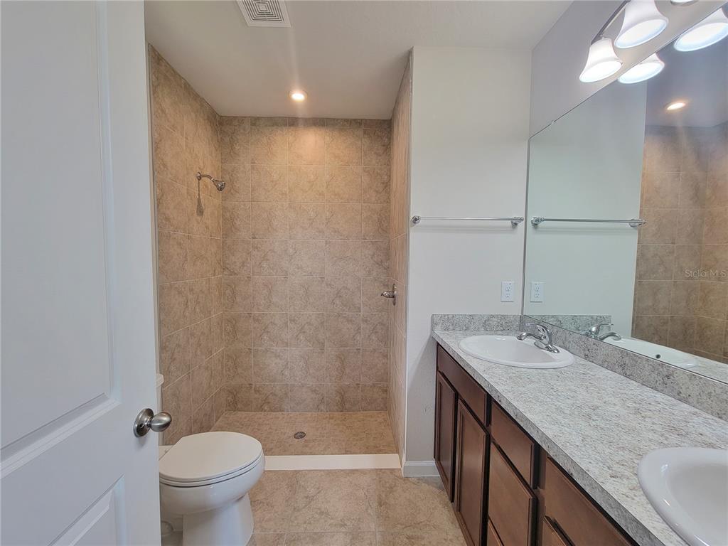 18008 Turning Leaf Circle Land O Lakes, FL 34638 - Photo 33 of 54 a bathroom with a granite countertop sink a toilet and shower