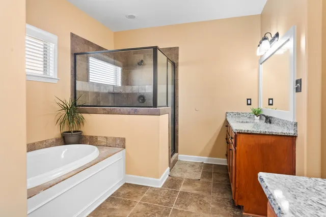 a bathroom with a granite countertop sink a bathtub and a mirror