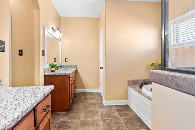 a spacious bathroom with a granite countertop sink and a bathtub