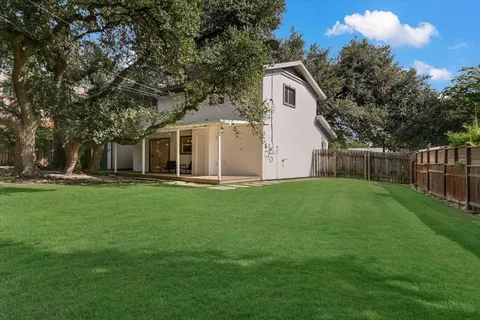 a view of a white house with a big yard and large trees
