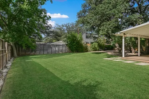 a view of a white house with a big yard and large trees