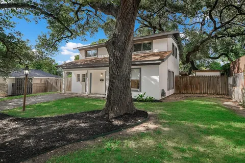 a view of a house with backyard and a tree