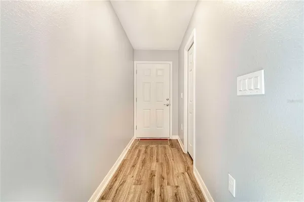 a view of a hallway with wooden floor and a bathroom