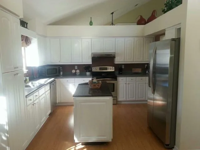 a kitchen with granite countertop a refrigerator stove and sink