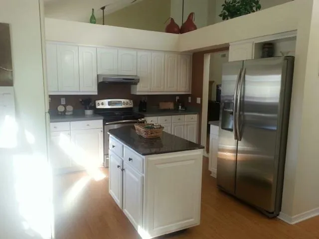 a kitchen with stainless steel appliances granite countertop a refrigerator a sink a stove and oven