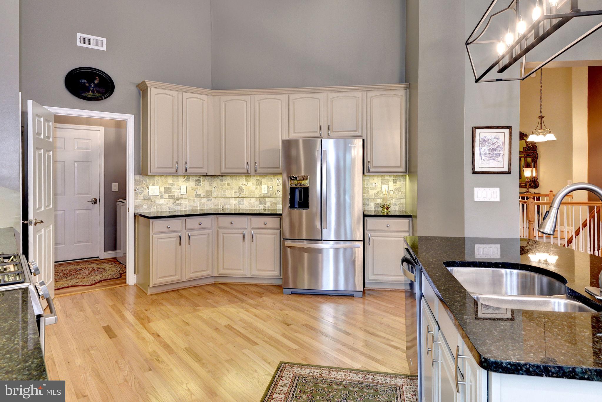 7100 Pinebrook Road Williamsburg, VA 23188 - Photo 25 of 86 a kitchen with granite countertop a refrigerator a stove a sink and white cabinets with wooden floor