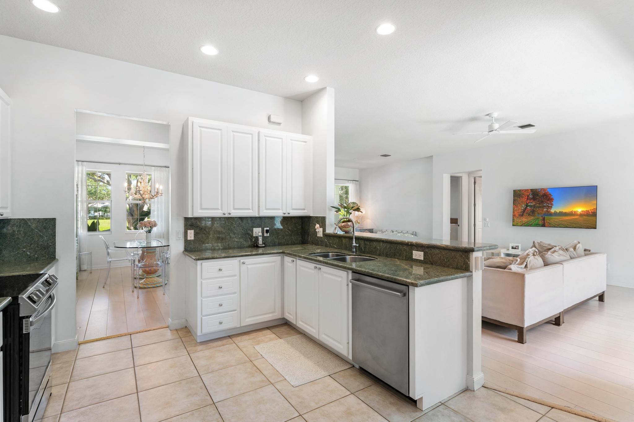 3446 West Mallory Boulevard Jupiter, FL 33458 - Photo 13 of 56 a kitchen with granite countertop a sink and white cabinets