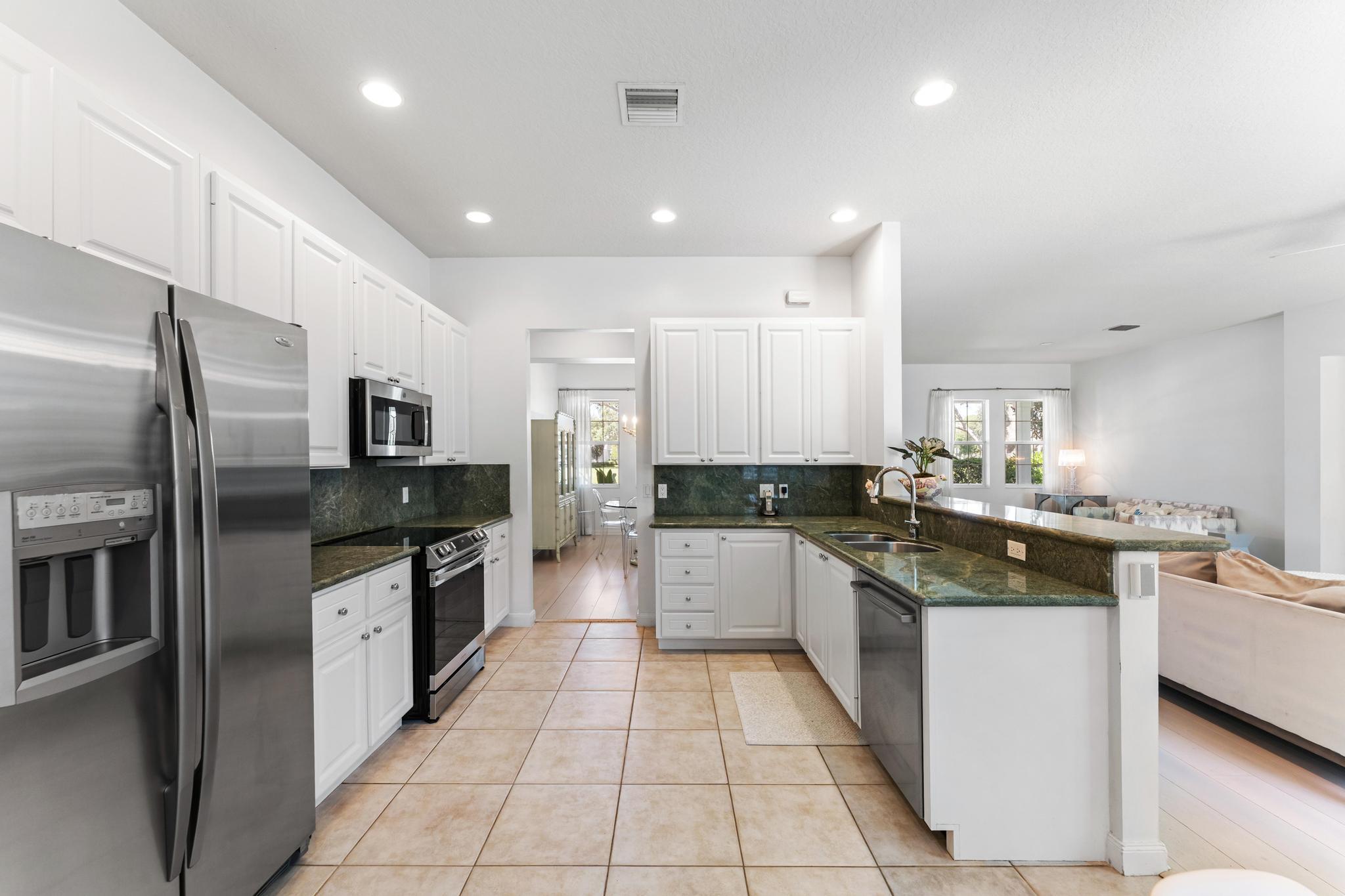 3446 West Mallory Boulevard Jupiter, FL 33458 - Photo 14 of 56 a kitchen with stainless steel appliances granite countertop a sink stove and refrigerator