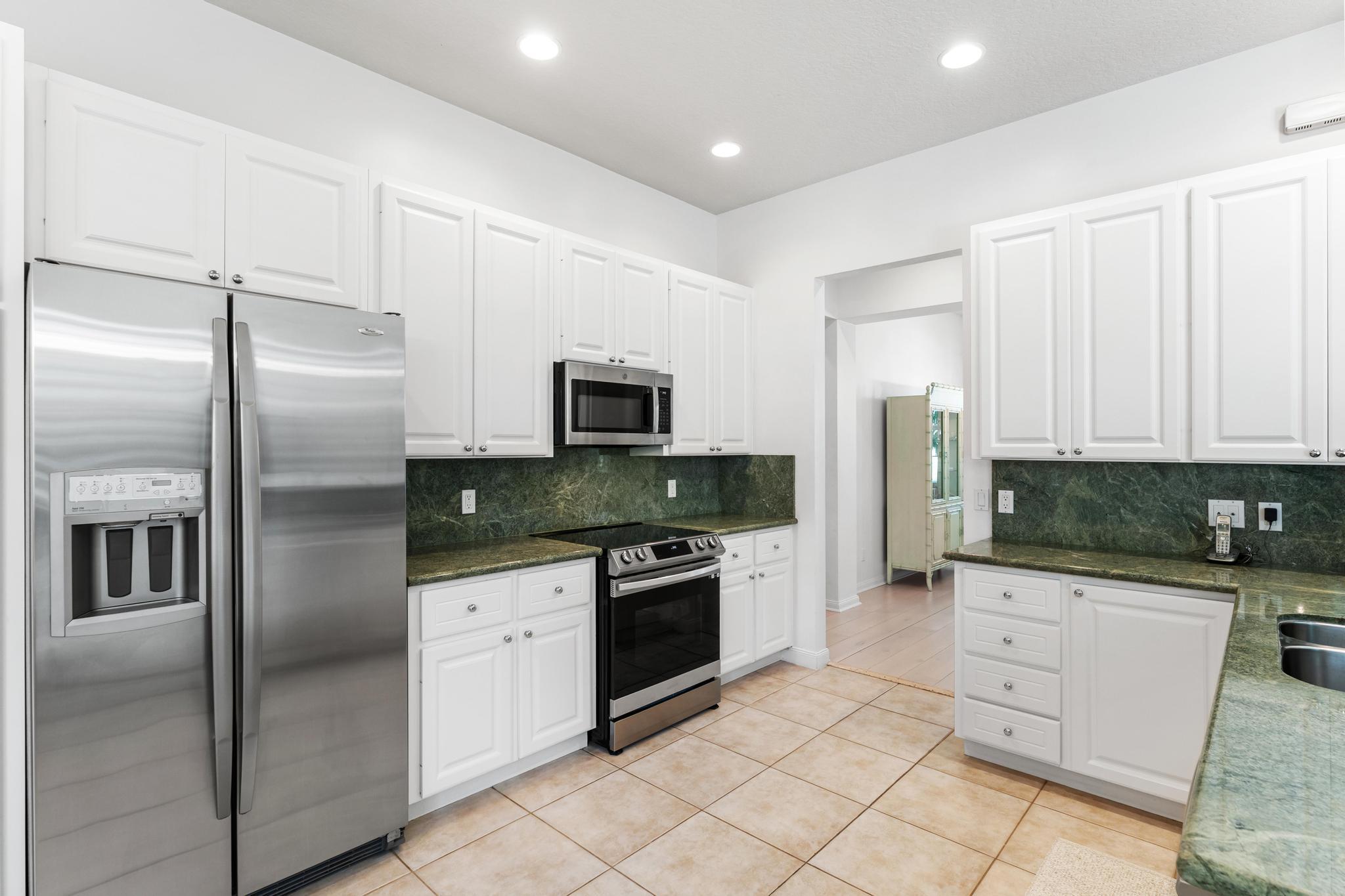 3446 West Mallory Boulevard Jupiter, FL 33458 - Photo 17 of 56 a kitchen with stainless steel appliances kitchen island granite countertop a refrigerator a stove a sink and dishwasher