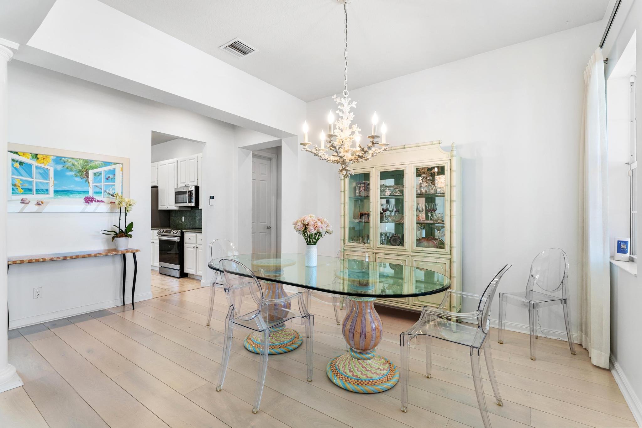 3446 West Mallory Boulevard Jupiter, FL 33458 - Photo 20 of 56 a dining room with wooden floor a chandelier a wooden table and chairs