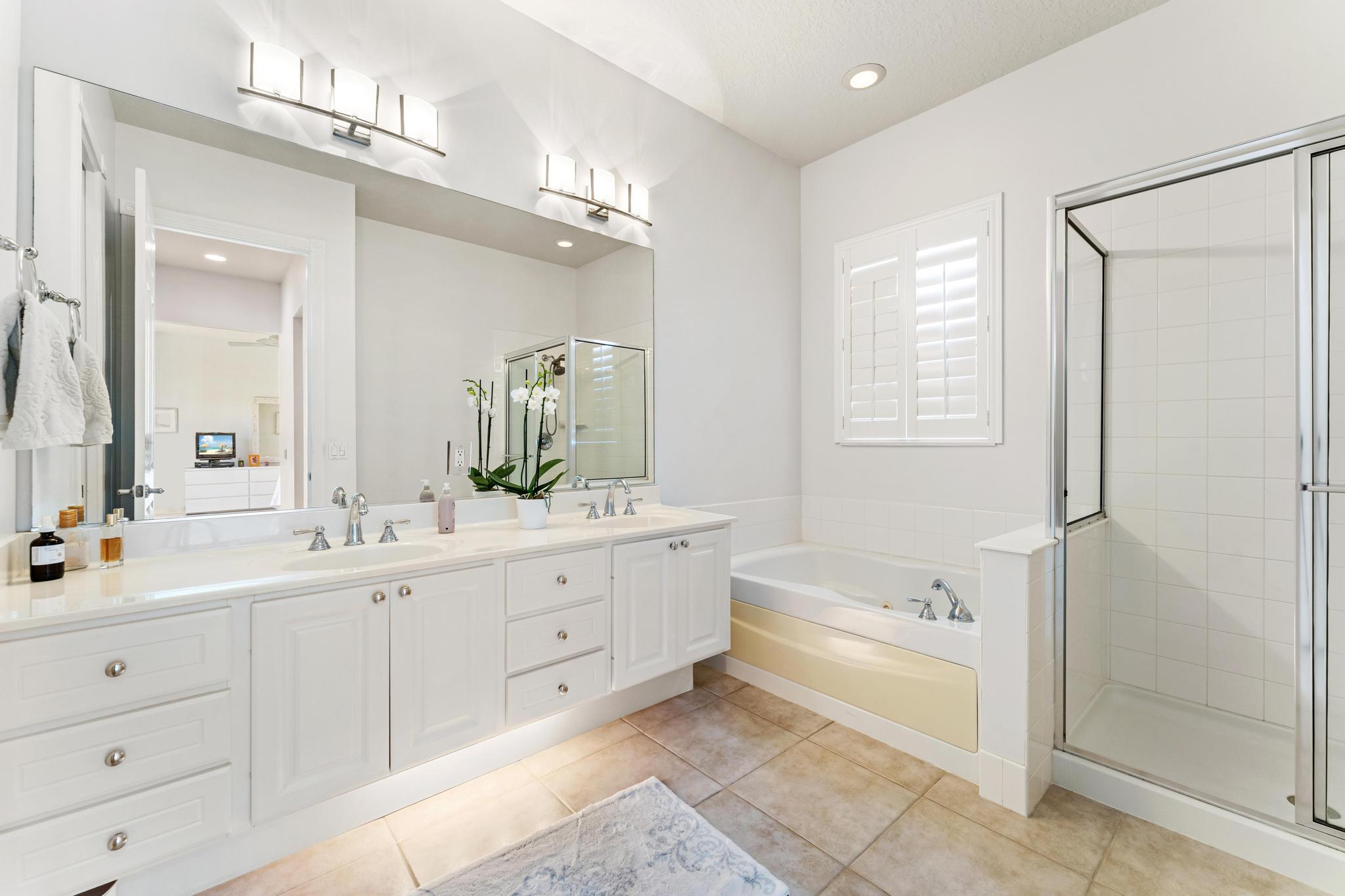 3446 West Mallory Boulevard Jupiter, FL 33458 - Photo 26 of 56 a spacious bathroom with a double vanity sink a mirror and a bathtub