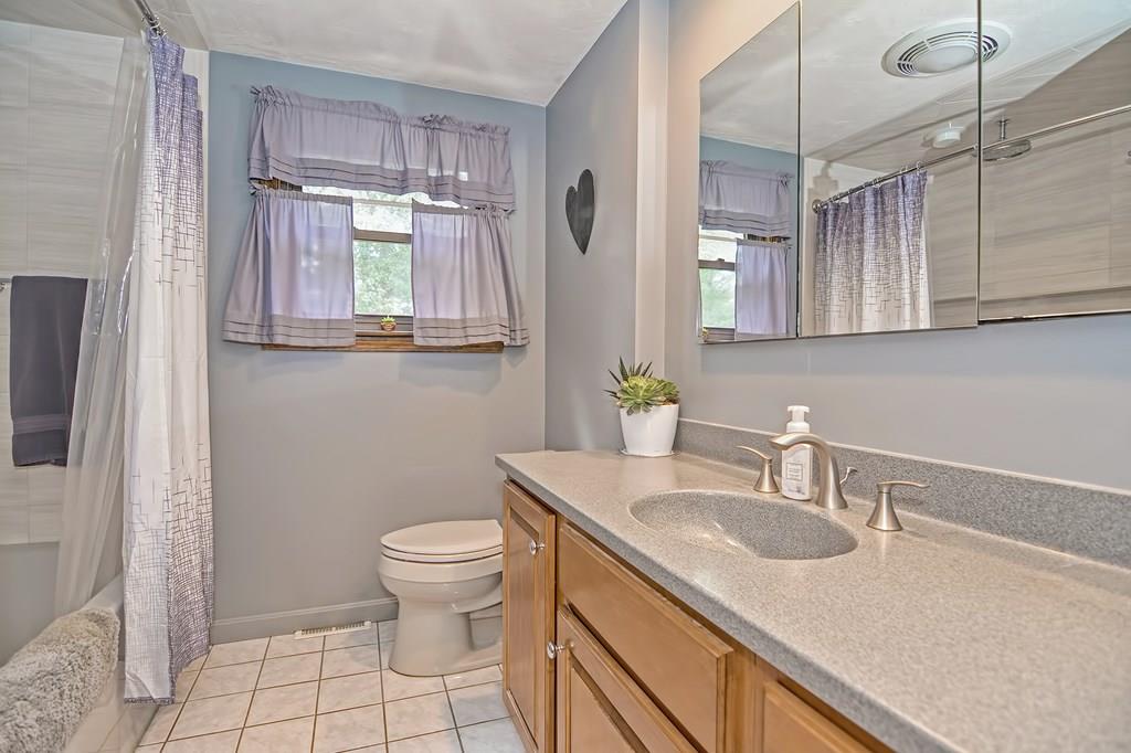 45 Frank Road Stoughton, MA 02072 - Photo 9 of 41 a bathroom with a granite countertop sink a toilet a mirror and vanity