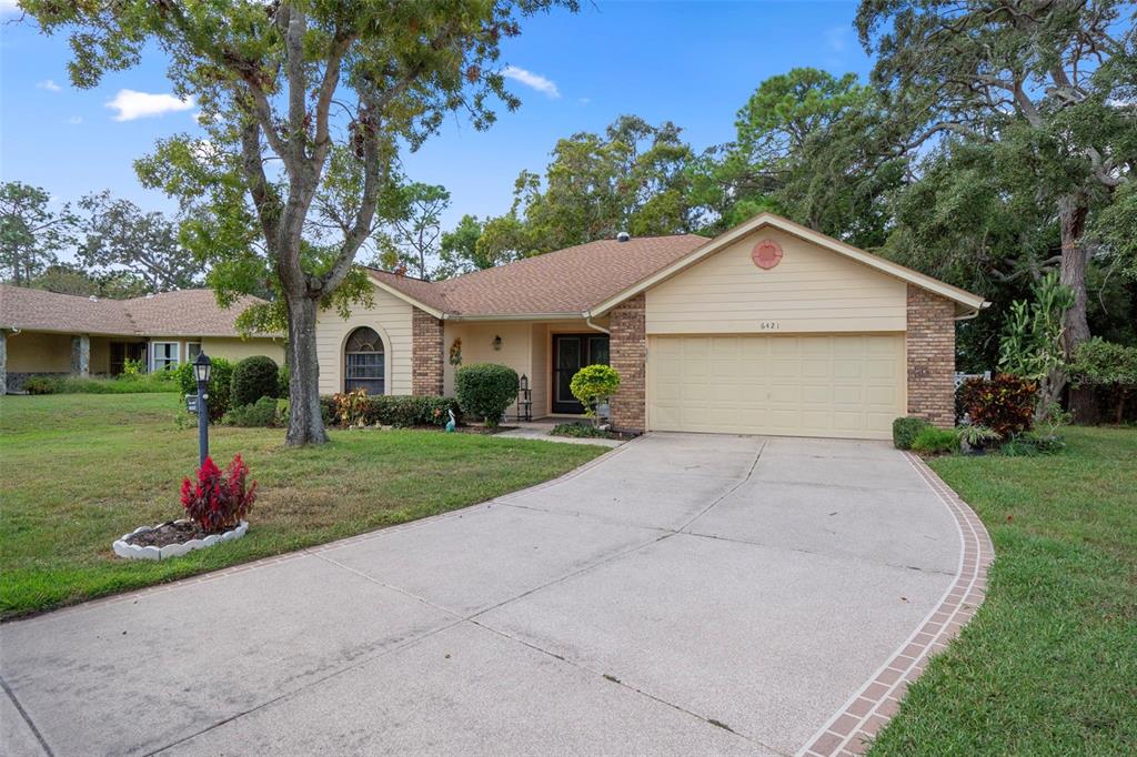 6421 Pine Meadows Drive Spring Hill, FL 34606 - Photo 1 of 61 a front view of a house with a yard and garage