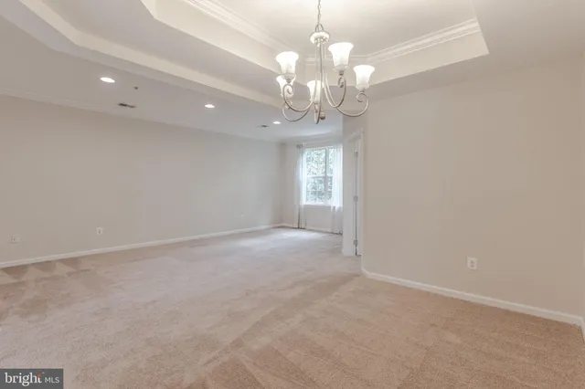 en empty room with a chandelier fan and a rug