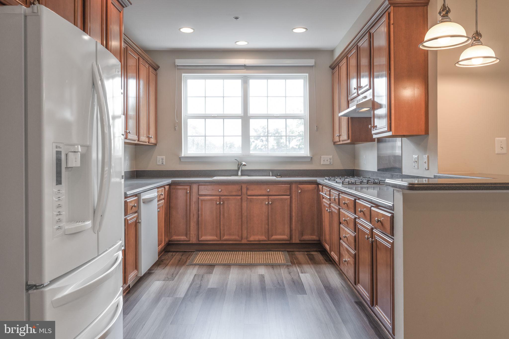 12404 B Liberty Bridge Road, Unit 12404B Fairfax, VA 22033 - Photo 4 of 43 a kitchen with stainless steel appliances granite countertop a stove a sink and a refrigerator with wooden floor