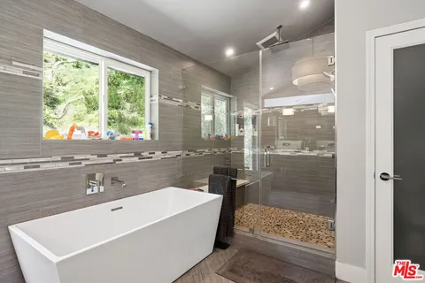 a bathroom with a tub a sink and a large mirror next to a window